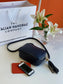 An image of a navy blue leather messenger bag with an orange purse and a mobile phone next to it. There is an Italian Handbag Company carrier bag in the background a vase of lilies.